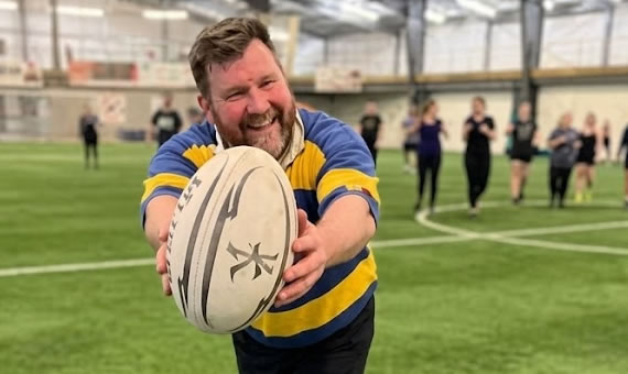 Person holding rugby ball and smiling